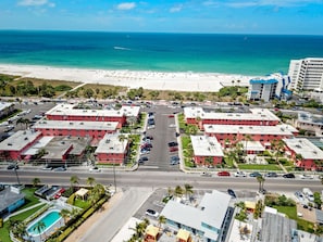 A coastal hotel with multiple red-roofed buildings, a parking lot, and a beach view. - 🌅 Gulf Winds #304 — Renovated 2BR Condo with Breathtaking Beach Views & Premium Upgrades (St Pete Beach)