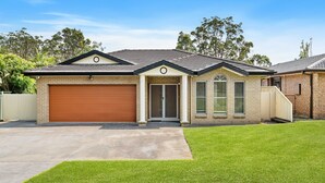Uma casa de dois andares com garagem, varanda da frente e gramado bem cuidado.