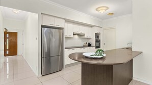 Cozinha moderna com armários brancos, eletrodomésticos de aço inoxidável e uma ilha central.