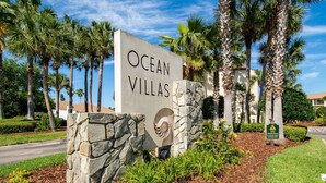 A sign for Ocean Villas with a stone base and a logo. - Views, Two Pools, Brand New Bathrooms, Updated Furniture, Direct Beach Access! $300 in Free Tickets! (St. Augustine Beach)