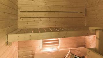 A sauna room with wooden walls and a bench.