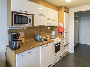 Une cuisine compacte équipée d’un four à micro-ondes, d’une machine à café, d’un évier, d’une cuisinière et de placards.