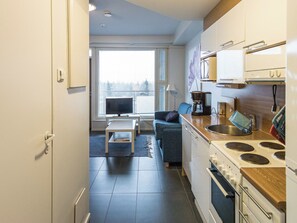 A compact kitchen with a stove, sink, and a dining area with a table and sofa.