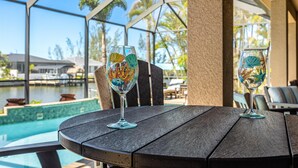 Two glass table settings with decorative patterns, a pool, and a covered outdoor area with chairs and tables.