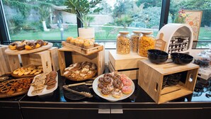 Buffet de l'esmorzar amb diverses pastes i productes de forn exposats sobre safates de fusta.