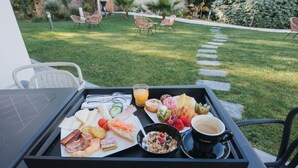 Un safata de petitdejuni amb diferents aliments i una tassa de cafè sobre una taula en un jardí.