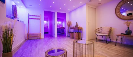 Un interior moderno con suelo de madera, un espejo redondo, muebles de mimbre y un banco.