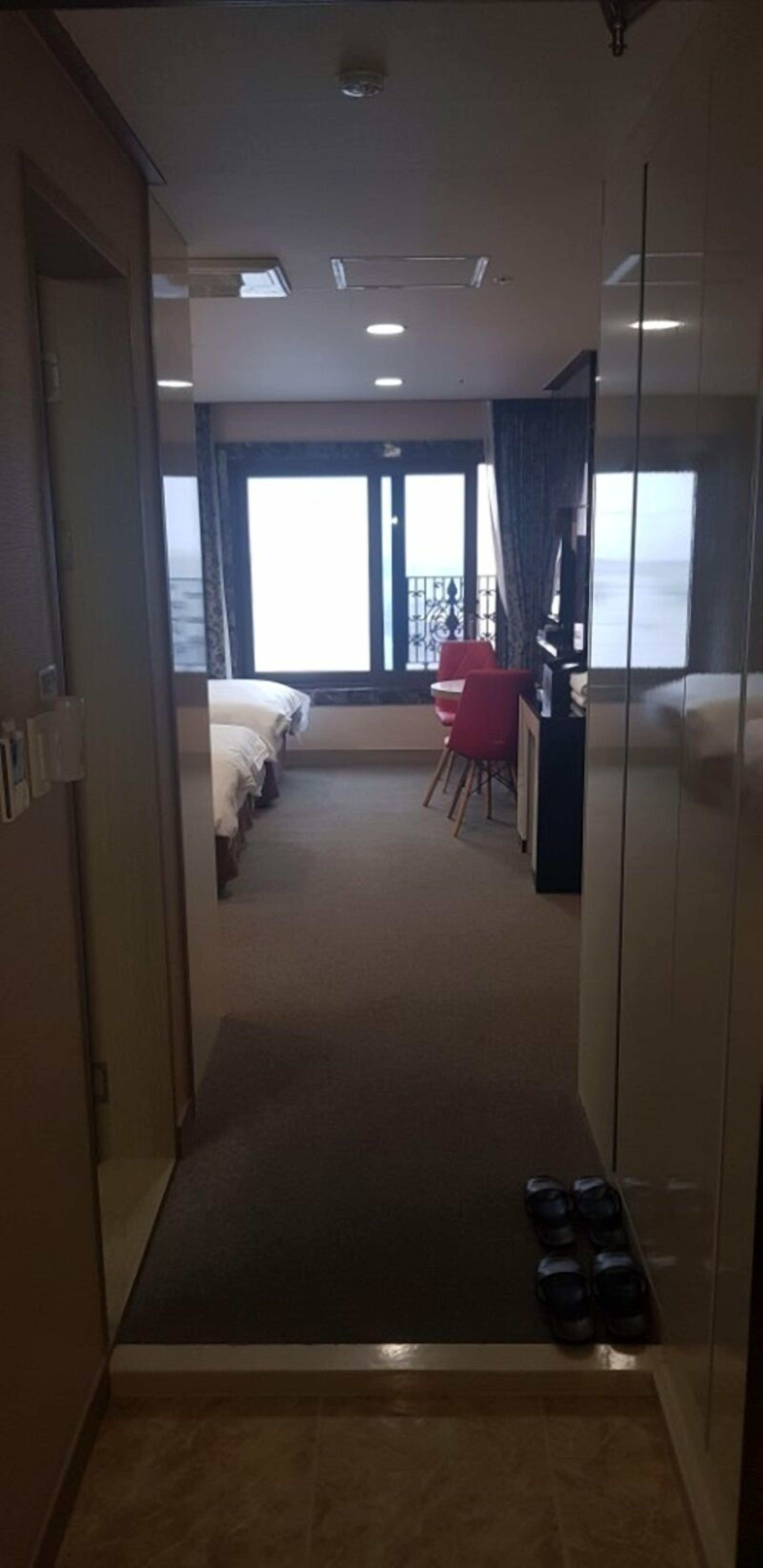A hotel room with a bed, a desk, and a view of the sea.