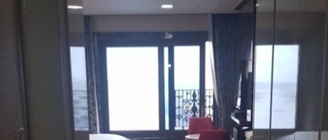 A hotel room with a bed, a desk, and a view of the sea.