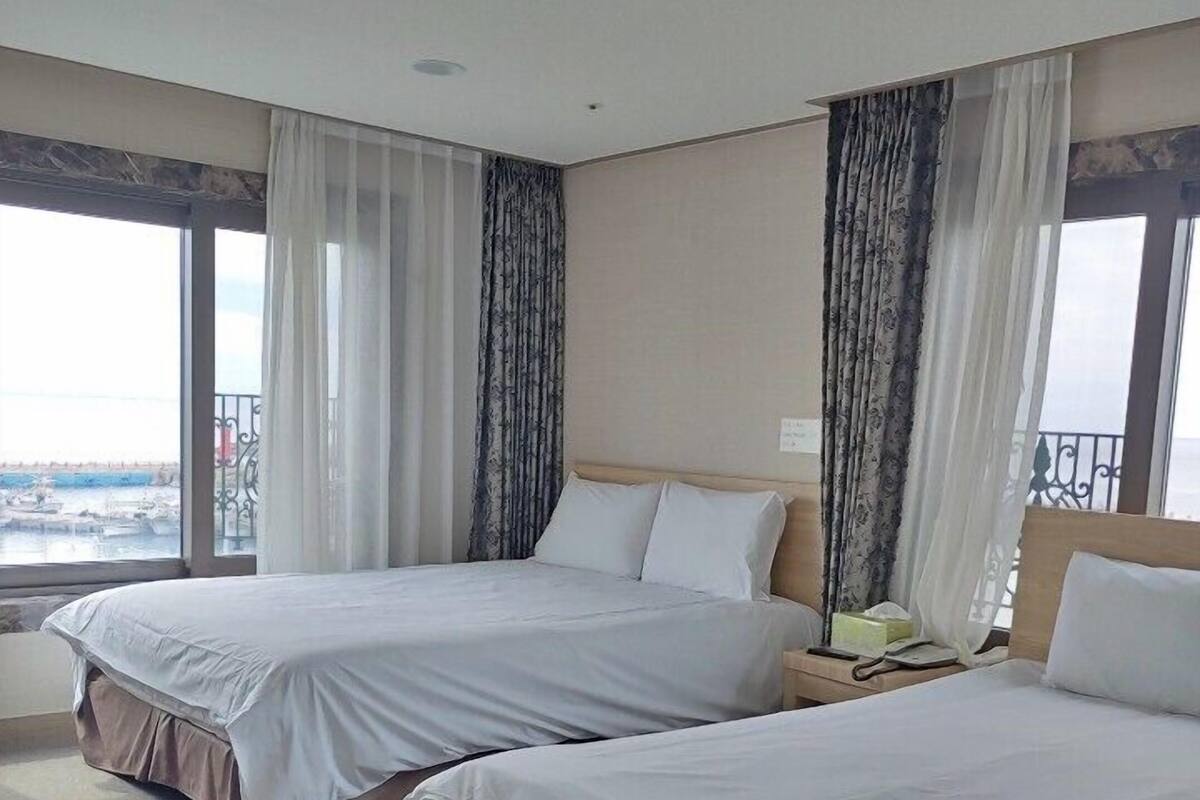 A hotel room with two beds, a view of the sea, and a balcony.