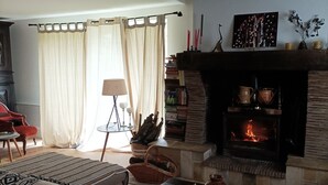 Een gezellige woonkamer met een open haard, een bank, een salontafel en een boekenkast.
