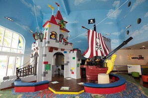 Un espace de jeux sur le thème de LEGO, avec un bateau de pirates, un château et un drapeau.