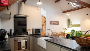 Une cuisine compacte équipée d’une cuisinière à gaz, d’un four à micro-ondes et d’appareils électroménagers en acier inoxydable.