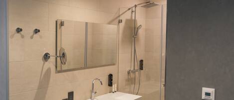 A modern bathroom with a glass-enclosed shower, a white sink, and a large mirror.