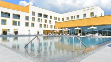 Una piscina al aire libre, sombrillas, sillones reclinables de piscina