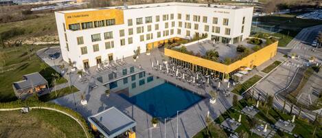 Un hotel con una piscina grande, varios balcones y un área de estacionamiento.