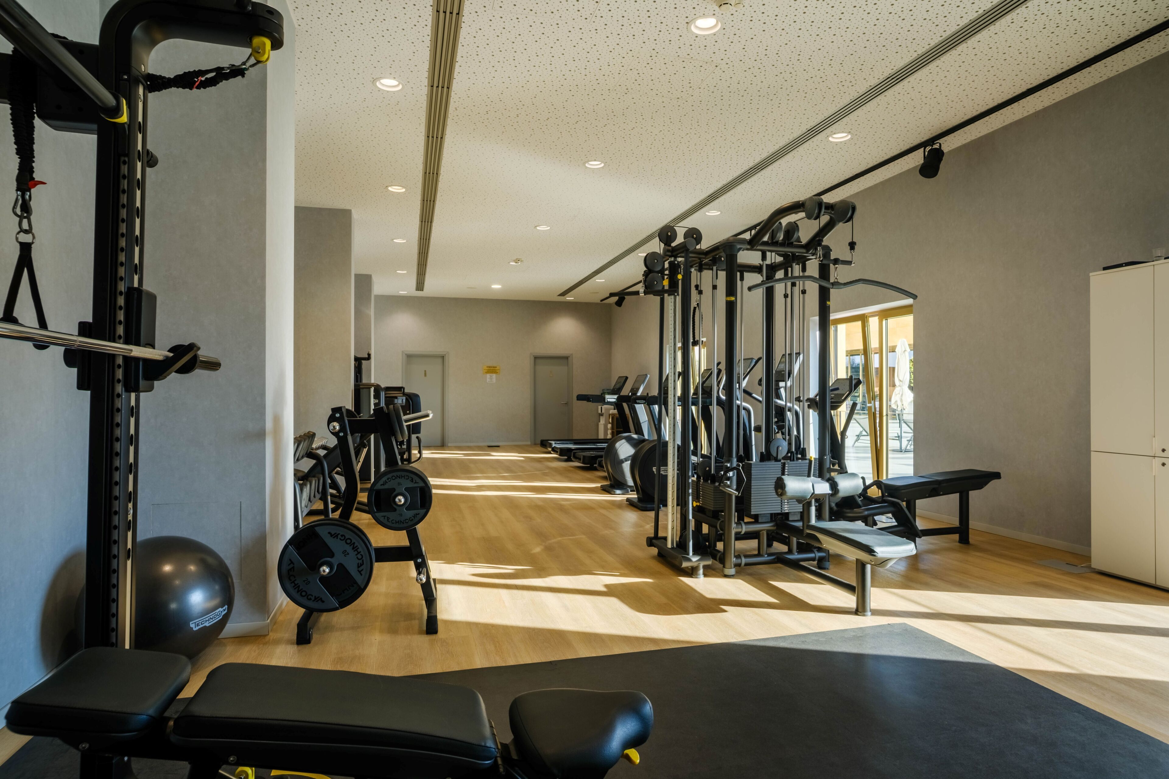 A gym with various exercise equipment, a bench, and a weightlifting area.