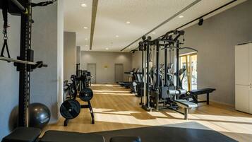 A gym with various exercise equipment, a bench, and a weightlifting area.
