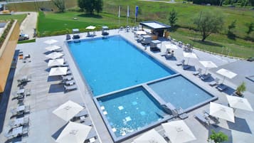 Una piscina al aire libre, sombrillas, sillones reclinables de piscina