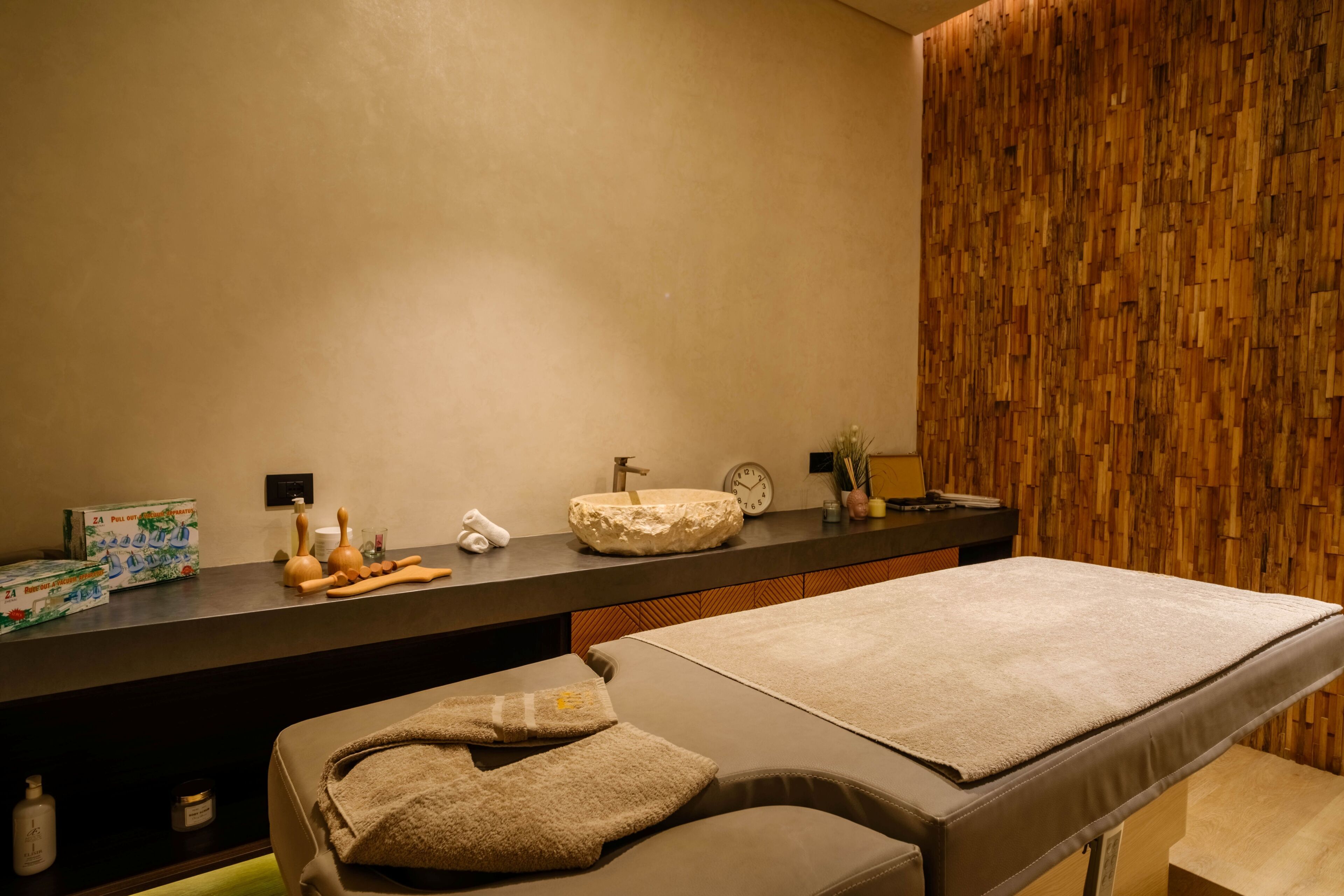Un cuarto de spa con una camilla de masaje, un lavamanos y una pared de madera.