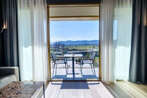 A balcony with a table and chairs, a sofa, and a view of a landscape with mountains and fields. - mk | hotel tirana (Preze)