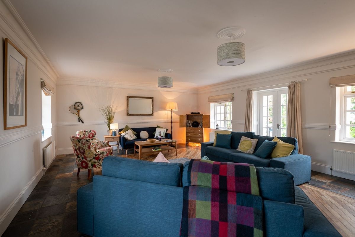 A living room with a blue sofa set, a wooden coffee table, and a patterned armchair.