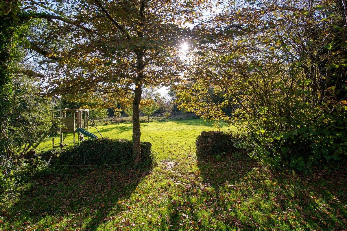 A park with a playground, a grassy area, and a tree-lined path.