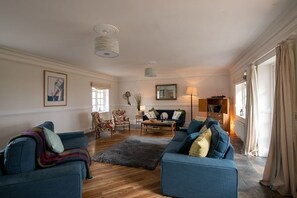 A living room with two sofas, a coffee table, and a rug. There is a chair, a lamp, and a mirror on the wall. - Ty Fferam Bailey: A beautiful 7 bed holiday home in Anglesey (Bodorgan)