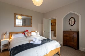 A bedroom with a bed, bedside table, dresser, and a mirror on the wall. - Ty Fferam Bailey: A beautiful 7 bed holiday home in Anglesey (Bodorgan)