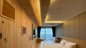 Een moderne hotelkamer met houten lambrisering, een groot bed, een televisie en uitzicht op de stad.
