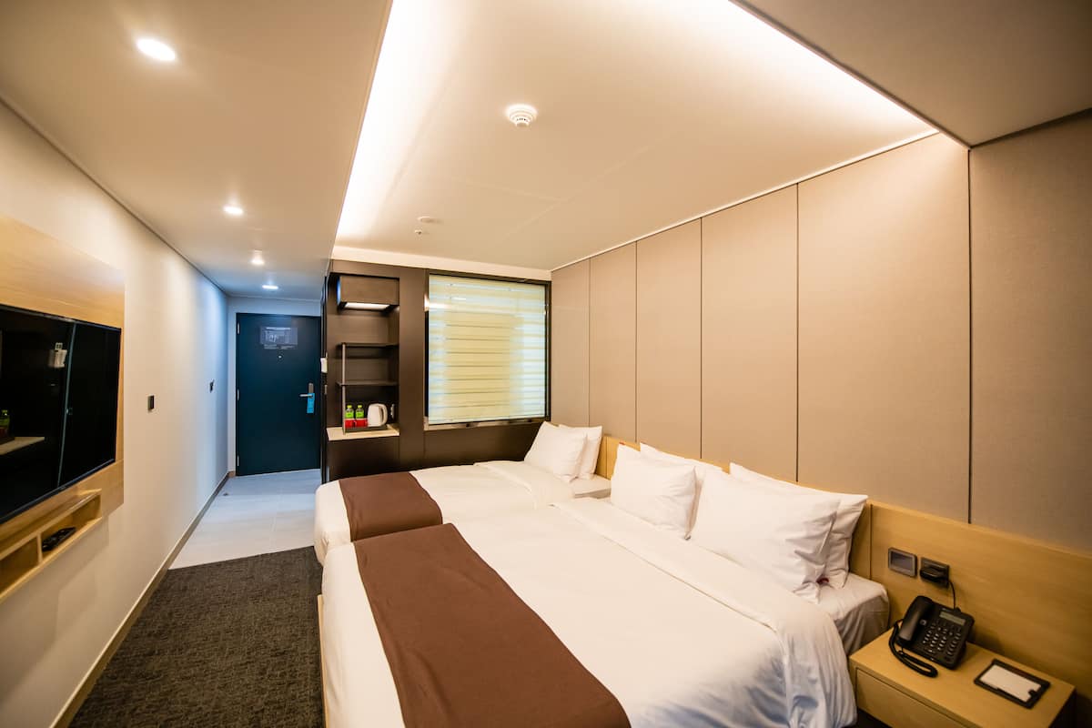 Una habitación de hotel con una cama grande, un escritorio con teléfono y un televisor a la izquierda.