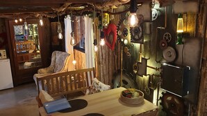 Una stanza accogliente con una panca di legno, un tavolo con un portatile e un muro decorato con ingranaggi e una lampada lava.