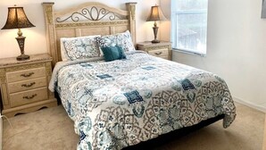 A bedroom with a bed, two nightstands, a window, and a lamp on each nightstand.