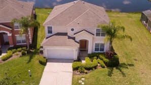 A two-story house with a garage, surrounded by well-maintained lawns and a small pond.