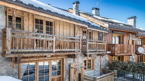 Un chalet de madera con balcones, paredes de piedra y techo cubierto de nieve.