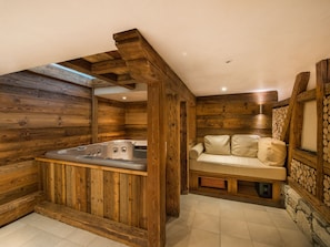 A wooden cabin with a hot tub and a sofa.