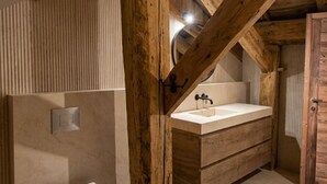 Un baño con tocador de madera, inodoro y espejo.