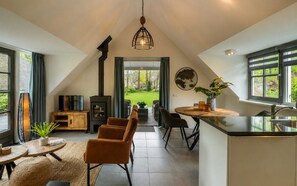 A modern kitchen with a large island, a dining area with chairs, and a view of the outdoors.