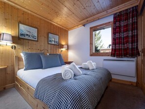 A wooden-paneled room with a bed, two wall-mounted lamps, and a window with plaid curtains. - Family Apartment in Central Val d'Isère - 80m², Near Slopes, 3 Bedrooms, WiFi, Parking (Val-d'Isère)