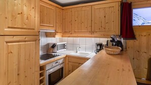 Une cuisine avec des meubles de rangement en bois, un four à micro-ondes, une cuisinière et un évier.