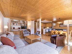 A cozy living room with a sofa, armchairs, a coffee table, and a bookshelf.