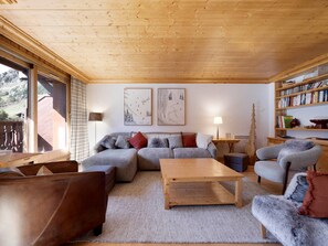 A cozy living room with a wooden ceiling, a sofa set, a coffee table, and a bookshelf. - Family Apartment in Central Val d'Isère - 80m², Near Slopes, 3 Bedrooms, WiFi, Parking (Val-d'Isère)