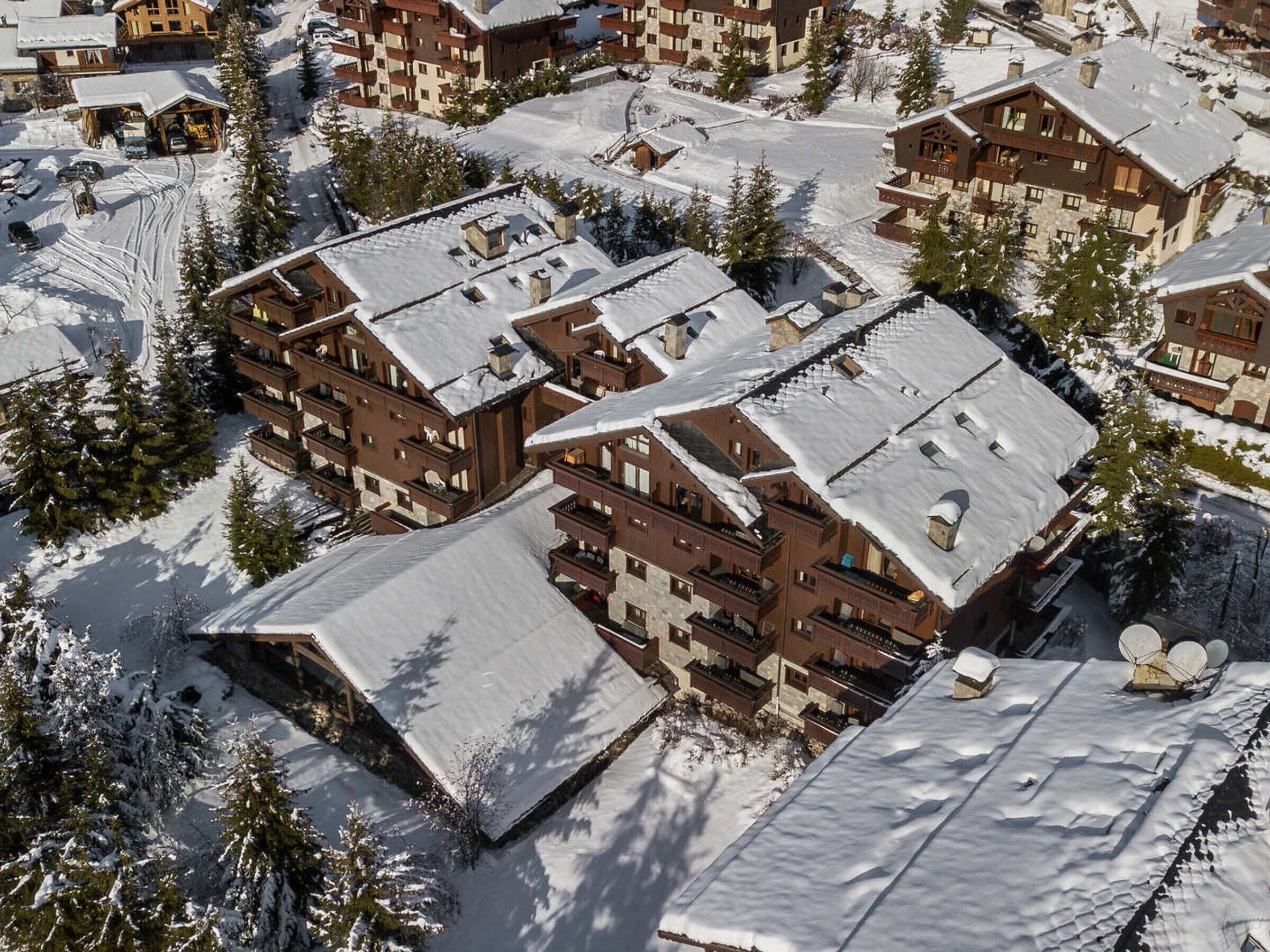 A snow-covered resort with multiple chalet-style buildings, ski lifts, and a ski slope.