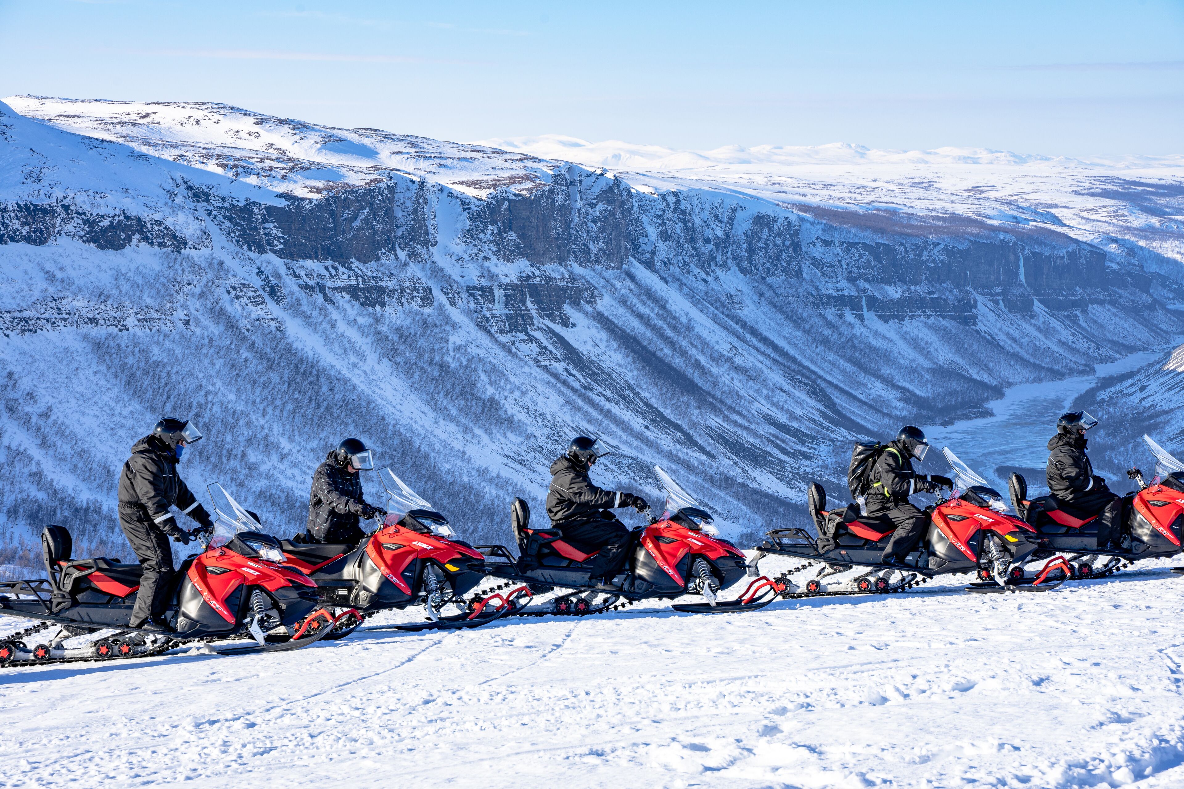 Un grupo de motos de nieve estacionadas en una ladera nevada de montaña.
