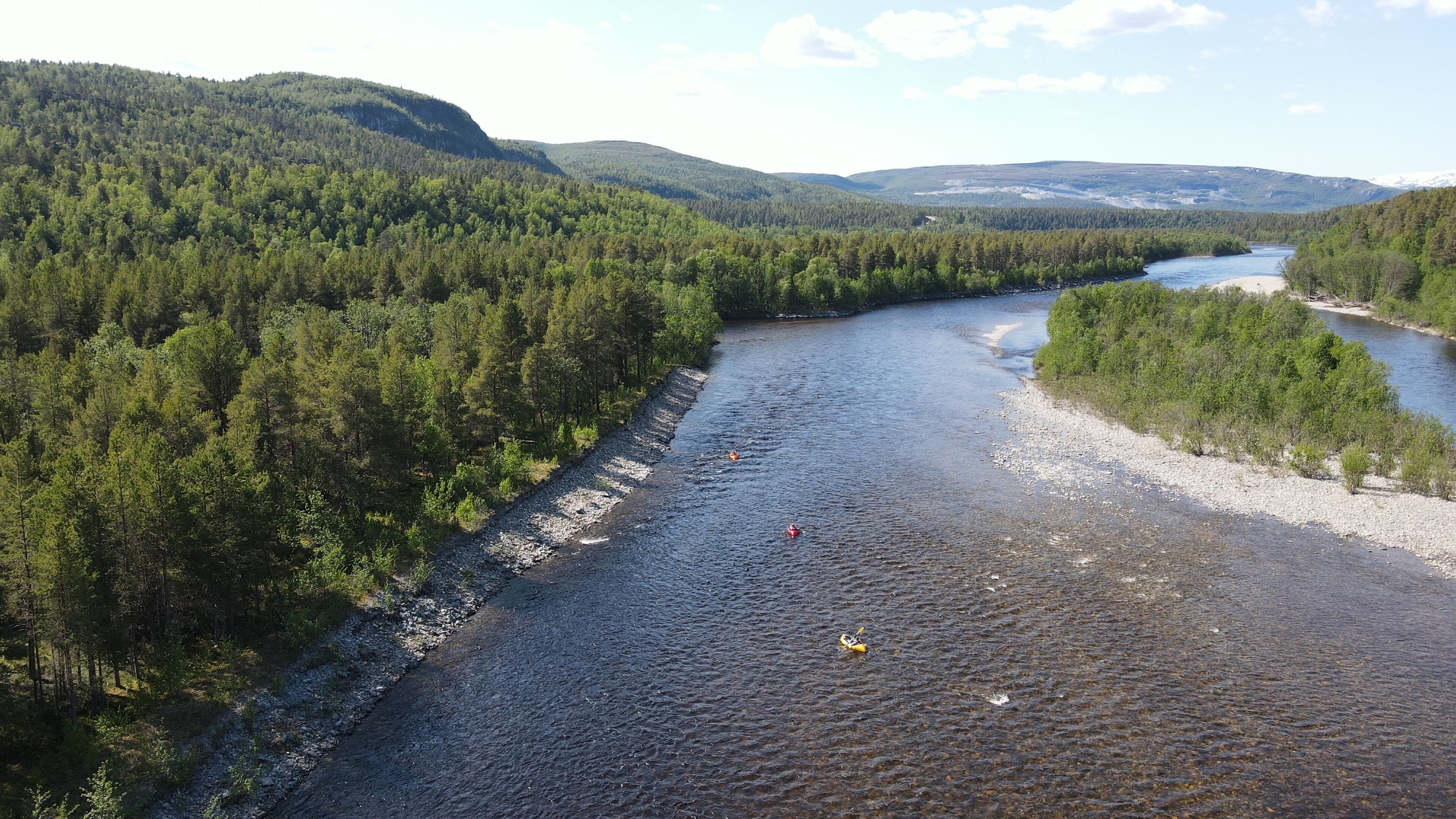 Ein Fluss, umgeben von dichtem Wald und Hügeln.