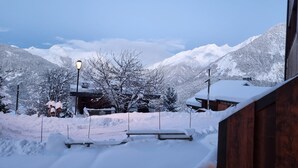 A snowy mountain landscape with a wooden building and a bench in the foreground.