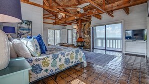 Une chambre spacieuse avec un grand lit, une cheminée en pierre et un balcon offrant une vue imprenable.