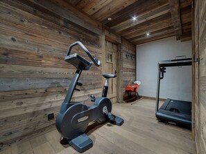 Ein Fitnessraum mit Trainingsgeräten, Holzwänden und einem Laufband.