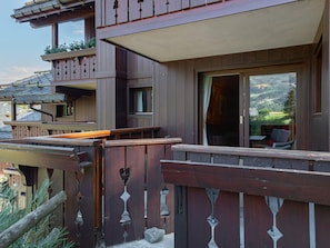 A wooden chalet with a balcony, a window with a view of the mountains, and a door leading inside. - Ski-in/ski-out apartment with terrace and pool access (Méribel)