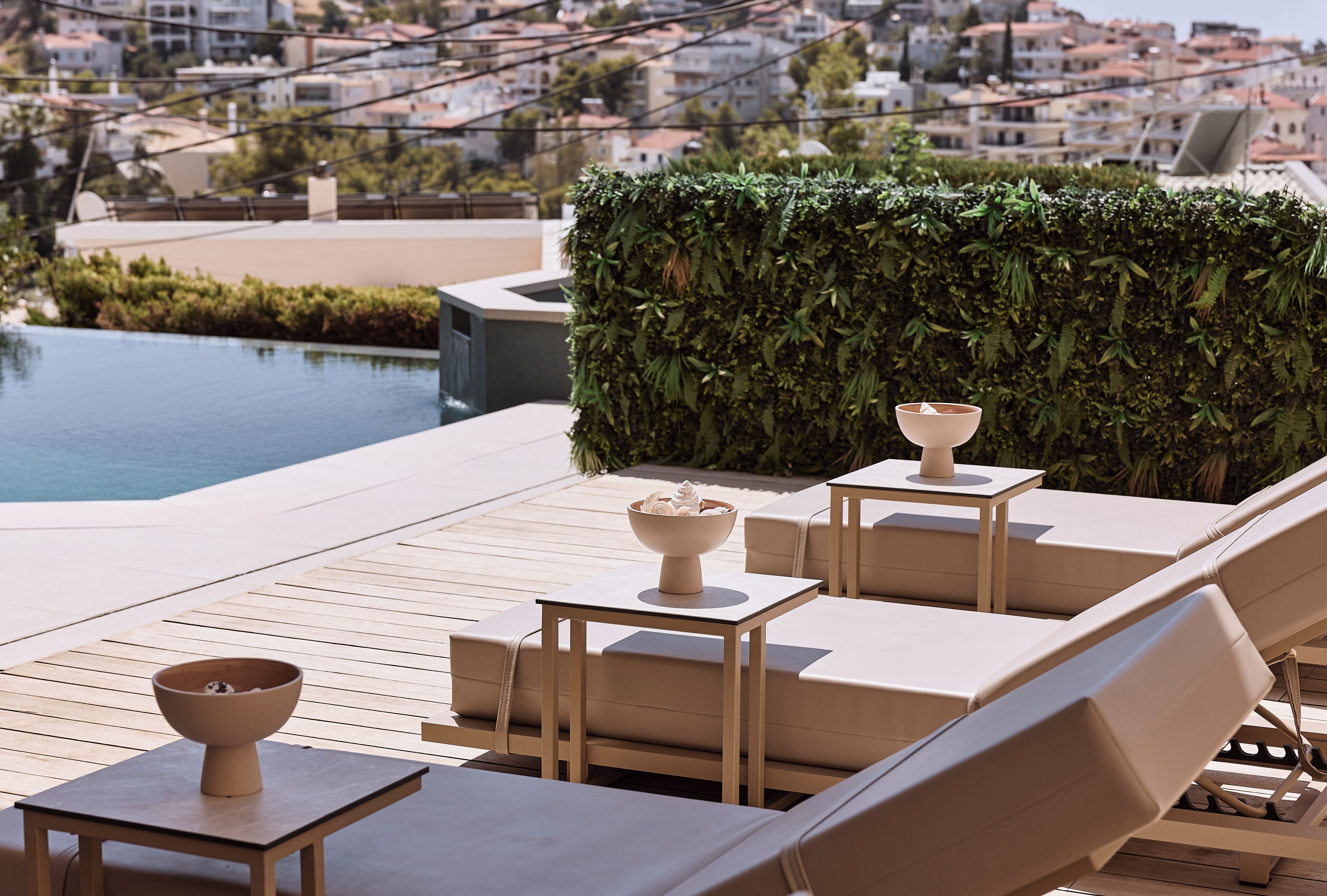 A rooftop lounge area with seating and a pool, overlooking a cityscape.